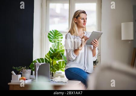 Junge Frau mit Tablet im Büro zuhause, arbeitet. Stockfoto