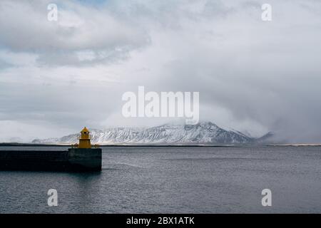 Leuchtturm am Seebrücke in reykjavik island. Leuchtturm gelb hellen Turm am Meer. Seehafen Navigationskonzept. Seetransport und Stockfoto