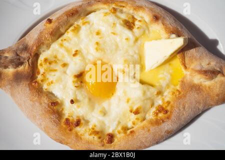 Adjarian khachapuri Nahaufnahme auf einem weißen Teller. Georgische nationale traditionelle Küche Stockfoto