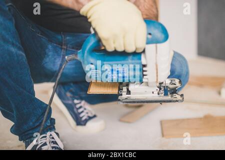 Ein Handwerker schneidet eine Laminatplatte mit einem elektrischen Stichsäge - Bodenbelag Stockfoto