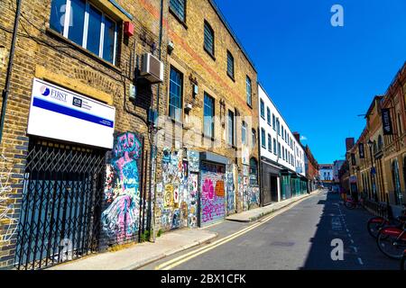 Ziegelwand mit Graffiti, Tags und Plakaten in Fashion Street, Spitalfields, London, Großbritannien Stockfoto