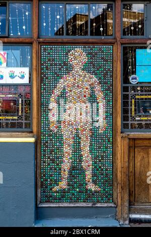 Menschliche Figur Silhouette aus alten Metall-Flaschenverschlüssen an der Fassade des Golden Heart Pub, Spitalfields, London, Großbritannien Stockfoto