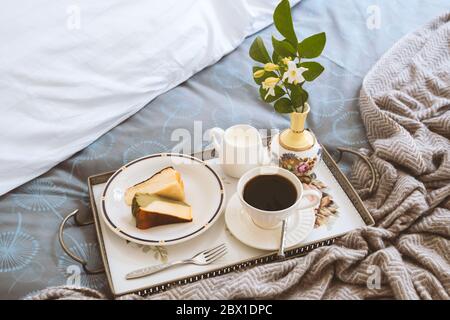 Frühstück im Bett Scheibe Cheesesescake mit einer Tasse Kaffee und Blumen in einem Tablett Stockfoto