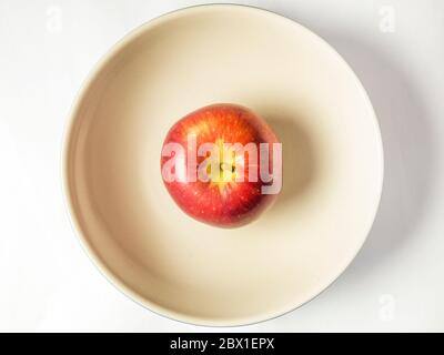 Ein einzelner Braeburn, der Apfel in einer großen Schüssel von oben auf einem weißen Hintergrund isoliert isst Stockfoto