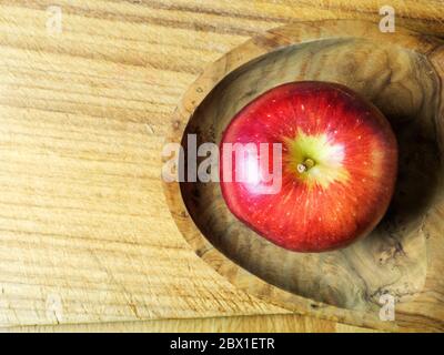 Ein einzelner Braeburn, der einen Apfel in einer Holzscheibe auf einem Schneidebrett mit Kopierfläche isst Stockfoto