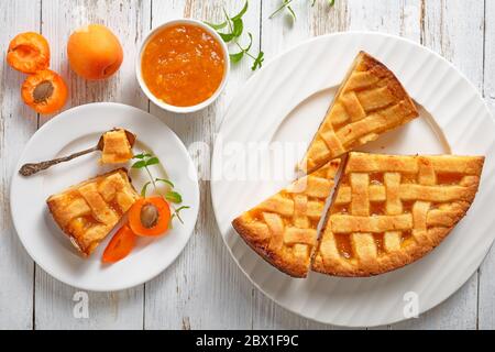 Nahaufnahme von Apricot-Shortkruste-Pie mit Gitterpie-Kruste auf weißen Tellern auf einem rustikalen Holztisch, flacher Lay, Blick von oben Stockfoto