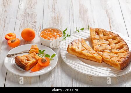 Nahaufnahme von Apricot-Shortkruste-Pie mit einem Gitter-Pie Kruste Belag auf weißen Platten auf einem rustikalen Holztisch, Blick auf Landschaft, Freiraum Stockfoto