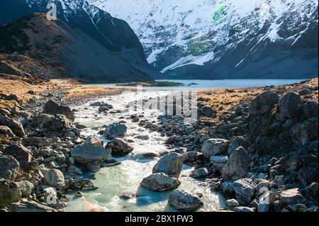 Gletscherbach im Hooker Valley, Aoraki Mount Cook National Park. Der milchig türkisfarbene Fluss fließt im Winter durch eine felsige Landschaft Stockfoto