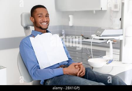 Glücklich schwarzen Kerl sitzt auf Zahnarztstuhl, die Zahnklinik Stockfoto