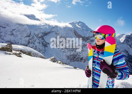 Portrait von niedlichen Mädchen in rosa Helm und Farbe Ski, Brille über hohen Bergspitzen Profil Ansicht Stockfoto