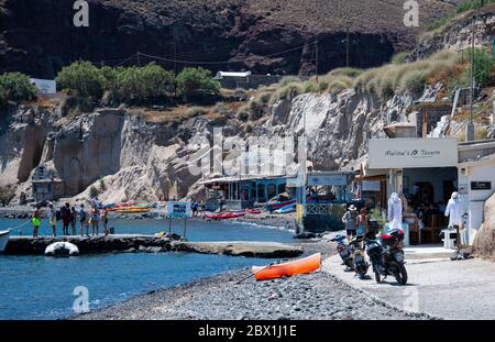 Akrotiri, Griechenland - Juli 19 2019: Touristen wandern entlang des Anlegesteg und vorbei an den Restaurants am Akrotiri Meer Stockfoto