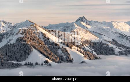 Blick auf schneebedeckte Berggipfel, Gampenkogel und Grosser Rettenstein im Abendlicht, hoher Nebel im Tal, Hochbrixen, Brixen im Stockfoto