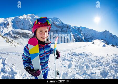Fun Porträt von Seite der lächelnden Skifahrer Mädchen mit Ski im Berg stehend tragen rosa Maske und Farbbrille Stockfoto