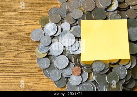 Haufen von Münzen mit leerem Etikett auf einem Holztisch. Finanzkonzept. Stockfoto