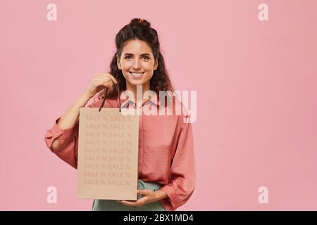 Porträt der schönen Frau beim Einkaufen auf Verkauf sie hält Papiertüte und lächelt an der Kamera Stockfoto