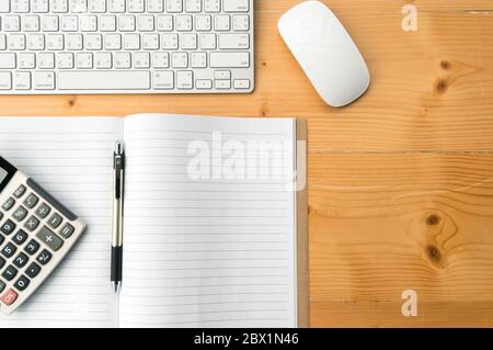 Top-Ansicht Arbeitsbereich mit leerem Notizbuch, Stift, Taschenrechner Tastatur und Maus auf Holztisch Hintergrund. Stockfoto