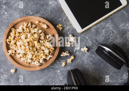 Popcorn mit weißem Tablet und Kopfhörer auf Grunge-Hintergrund. Stockfoto