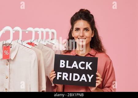 Porträt der jungen Frau mit lockigen Haaren halten Schild mit Black Friday während im Geschäft stehen Stockfoto
