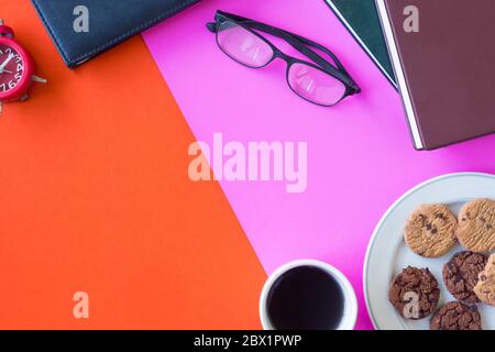 Bücher, Gläser, Uhr, Kekse und Kaffeetasse auf buntem Hintergrund. Freier Platz für Text Stockfoto