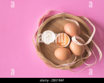 Eier mit Maßband auf rosa Hintergrund. Stockfoto