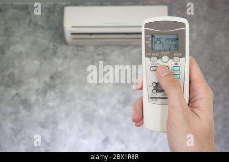 Fernbedienung mit der Hand vor der Klimaanlage. Stockfoto