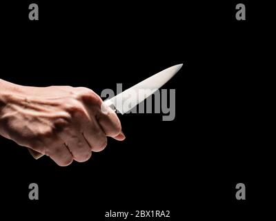 Männliche Hand hält Messer auf schwarzem Hintergrund. Stockfoto