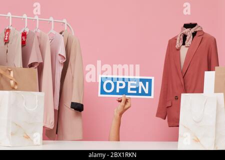 Bild von weiblicher Hand halten Plakat mit Open Zeichen in der Kleidung zu kaufen Stockfoto