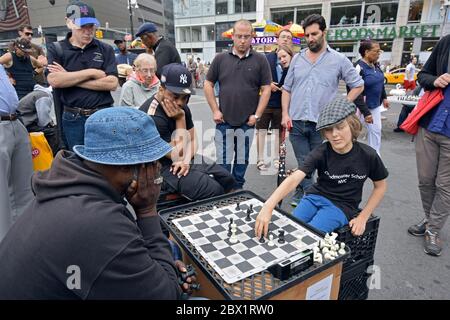 Ein junger Mann zieht eine Menge und spielt Schach gegen einen älteren Mann. Im Union Square Park. Stockfoto