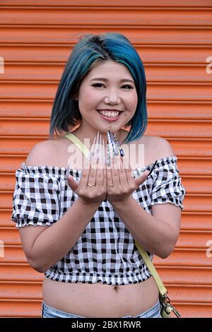 Eine junge Japanerin mit blauem Haar und außergewöhnlich langen Fingernägeln auf Coney Island, Brooklyn, New York. Stockfoto