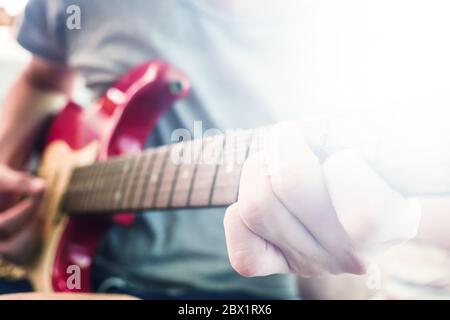 Nahaufnahme von männlichen Händen spielen E-Gitarre, Flare aus dem Sonnenlicht, Selective Focus Stockfoto