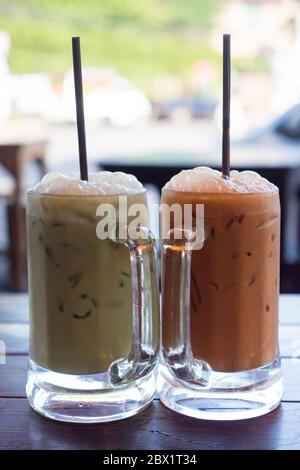 Milchgrüner Tee und milchthai-Tee in Glaskrügen auf Holztisch. Stockfoto