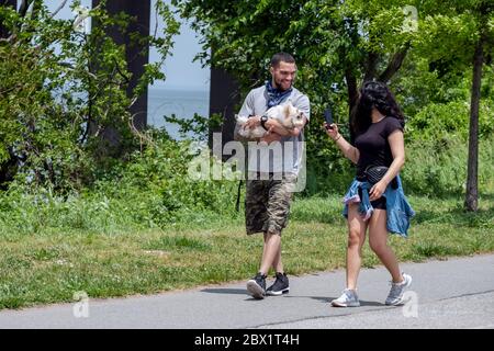 Eine junge Dame macht ein Foto oh er Begleiter und seinen oder ihren Hund. Im Little Bay Park in Whitestone, Queens, New York City. Stockfoto