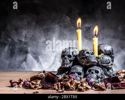 Schädel mit brennenden Kerzen und getrockneten Blüten auf dunklem Hintergrund. Stockfoto