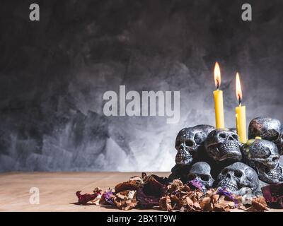 Schädel mit brennenden Kerzen und getrockneten Blüten auf dunklem Hintergrund. Stockfoto