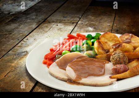 Aufnahme von traditionellen britischen Braten gefüllte Lende von Schweinefleisch mit Gemüse in einem weißen Teller auf Holzhintergrund. Stockfoto