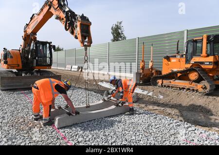 Stralsund, Deutschland. Juni 2020. Arbeiter legen Betonschwellen mit Hilfe eines Raupenbaggers. Die Deutsche Bahn investiert in Stralsund 22 Millionen Euro in den Bau einer Lager- und Behandlungsanlage für Fernzüge. In der Werkstatt sollen gleichzeitig bis zu sieben ICE-Züge gereinigt, gewartet und auf die nächste Fahrt vorbereitet werden, teilte das Unternehmen mit. Quelle: Stefan Sauer/dpa/Alamy Live News Stockfoto