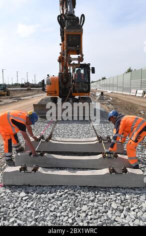 Stralsund, Deutschland. Juni 2020. Arbeiter legen Betonschwellen mit Hilfe eines Raupenbaggers. Die Deutsche Bahn investiert in Stralsund 22 Millionen Euro in den Bau einer Lager- und Behandlungsanlage für Fernzüge. In der Werkstatt sollen gleichzeitig bis zu sieben ICE-Züge gereinigt, gewartet und auf die nächste Fahrt vorbereitet werden, teilte das Unternehmen mit. Quelle: Stefan Sauer/dpa/Alamy Live News Stockfoto