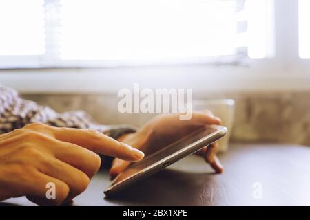 Nahaufnahme der männlichen Händen mit Tablet-PC auf dem Schreibtisch, getönt mit Sonnenlicht. Stockfoto
