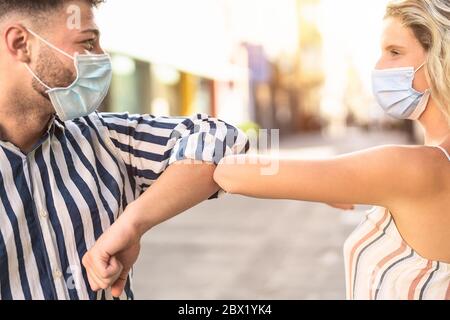 Junge Freunde tragen Gesicht chirurgische Maske tun neue soziale Distanzierung begrüßen mit Ellbogen zur Verhinderung Corona-Virus Ausbruch Stockfoto