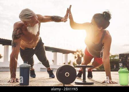 Fitness-Paar tun Liegestützen Übung im Freien - Happy Athleten machen Workout-Session bei Sonnenuntergang draußen Stockfoto