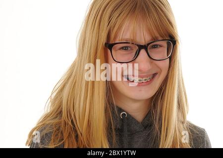 Hübsches blondes Teenager-Mädchen trägt Brille und sichtbare Zahnspangen auf ihren Zähnen isoliert auf weißem Hintergrund Stockfoto