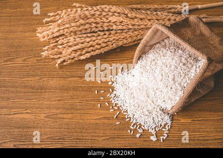 Nahaufnahme von rohem Reis in einem Sackleinen auf einem Holztisch. Stockfoto