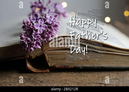 Worte Happy Fathers Day offenes antikes Buch mit Frühlingssommerblumen, Bokeh ist auf dem Hintergrund. Geburtstagskarte Konzept Stockfoto