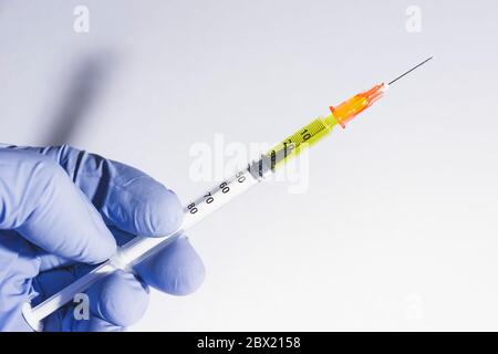 Handschuhhandgriff, der eine Spritze für Impfstoff oder Insulin hält. Weißer Hintergrund. Konzepte der Gesundheit, Coronarivus oder Drogen Stockfoto
