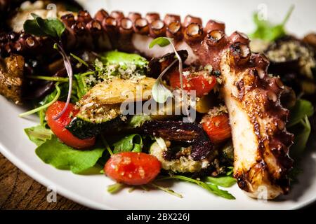 Warmer Krake-Salat mit gebratenem Gemüse und Aji-Sauce auf weißem Teller. Köstliche gesunde mediterrane traditionelle Meeresfrüchte Nahaufnahme auf einem serviert Stockfoto