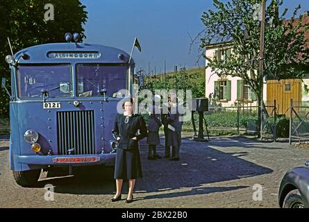 Eine Frau steht neben einem Bus, der nach Helsingborg, Schweden c. 1950. Sie trägt modische Kleidung. Andere Passagiere warten im Hintergrund. Der Bus ist ein Scania Vabis (später Teil von Saab-Scania). Es hat zwei schwedische Fahnen oder Wimpel an der Vorderseite befestigt. Helsingborg (es wurde zwischen 1912 und 1970 Hälsingborg geschrieben) ist eine Stadt in Scania, Schweden und ist Schwedens nächster Punkt zu Dänemark. Stockfoto