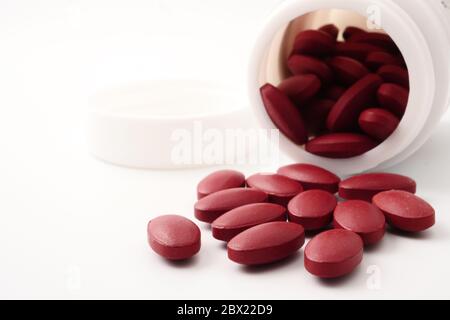 Rote Vitaminpillen, die aus der Flasche auf weißem Hintergrund ausgießen. Stockfoto