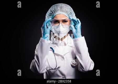 Foto von serious Dame doc halten Arme auf schützende Kunststoff-Brille bereit bereiten Operation Tragen Handschuhe Maske Mantel Gesichtsbrille Spezifikationen chirurgische Kappe Stockfoto