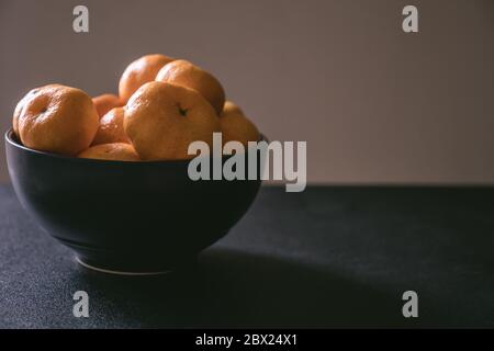Frische Mandarinen in Schale, Orangenfrüchte auf dunklem Hintergrund. Stockfoto