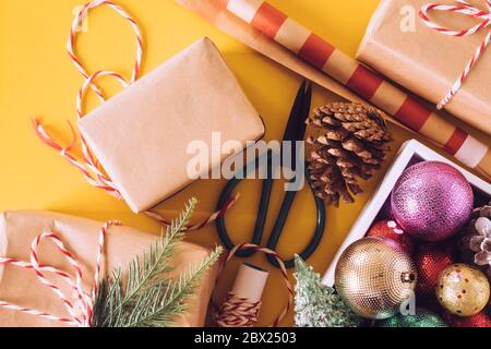 Zubereitungsgeschenke mit Weihnachtsschmuck auf gelbem Hintergrund. Stockfoto